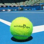 Na obrazku widnieje piłka tenisowa z napisem 'australian open' na tle kortu