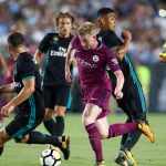 obrazek przedstawia piłkarzy Real Madryt próbujących odebrać piłkę Kevinowi De Bruyne