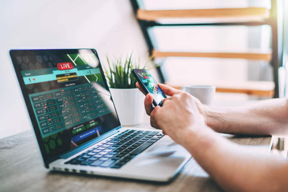 Na obrazku widnieją ręce gracza, który obstawia mecze on-line